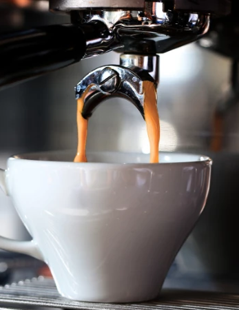 An espresso machine pours two streams into a white cup, steaming hot coffee ready to drink, as the shot flows from the portafilter.